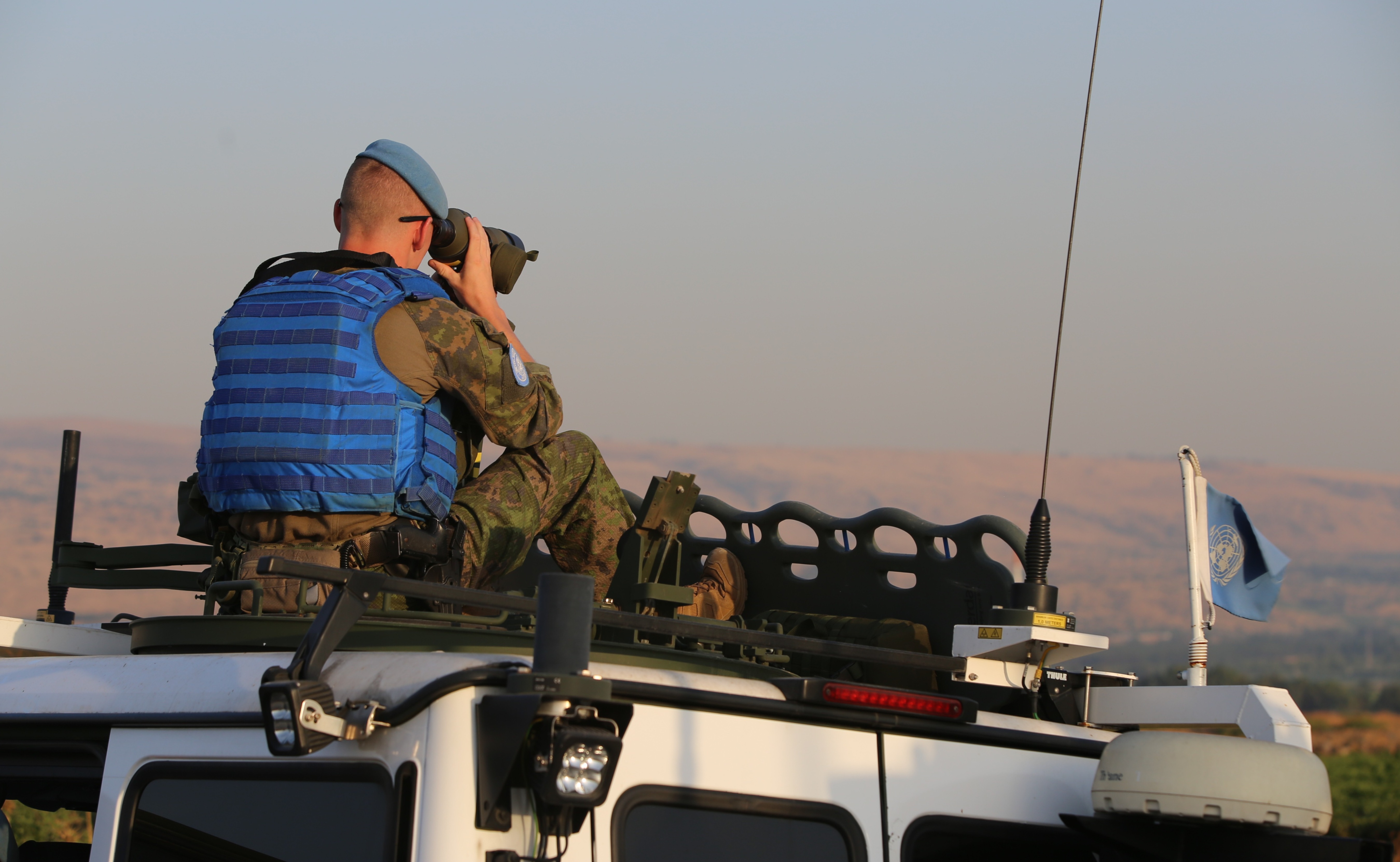 YK:n rauhanturvaaja tarkkailee ympäristöä kiikarilla.
