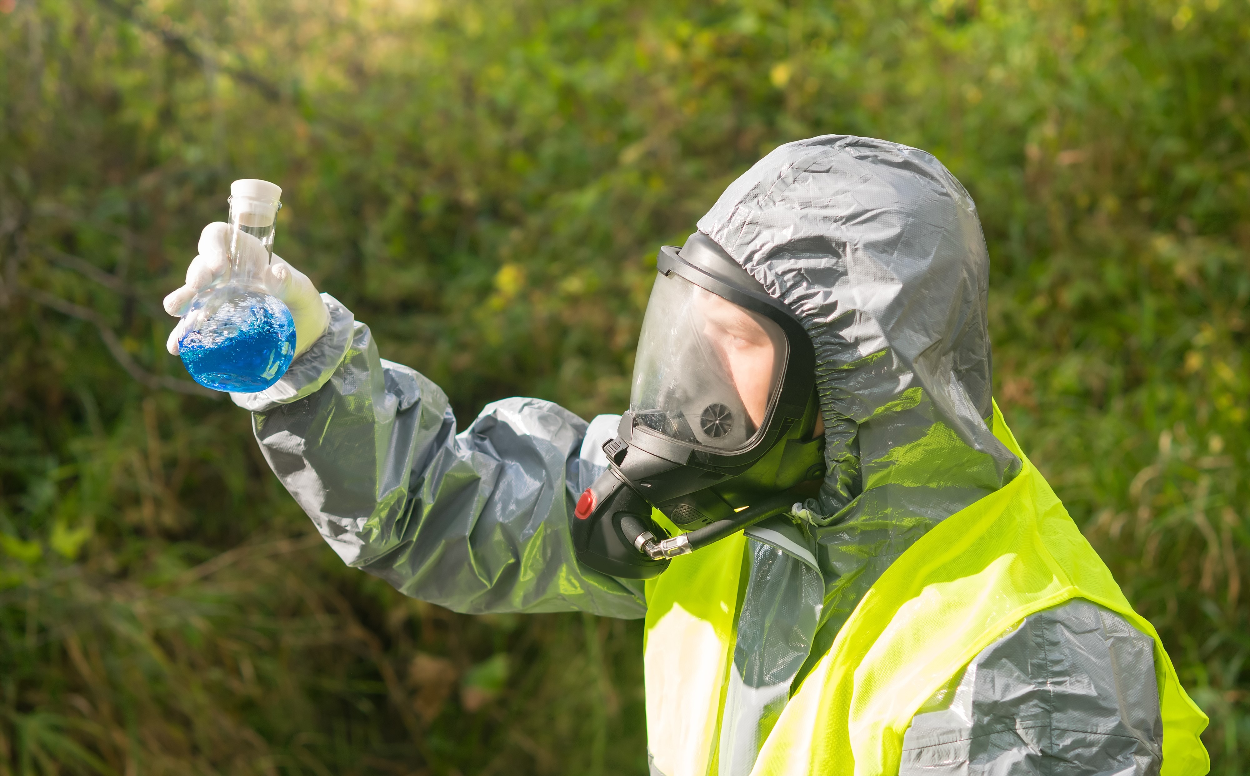 En person som är klädd i skyddsdräkt och andningsskydd undersöker kemikalien.