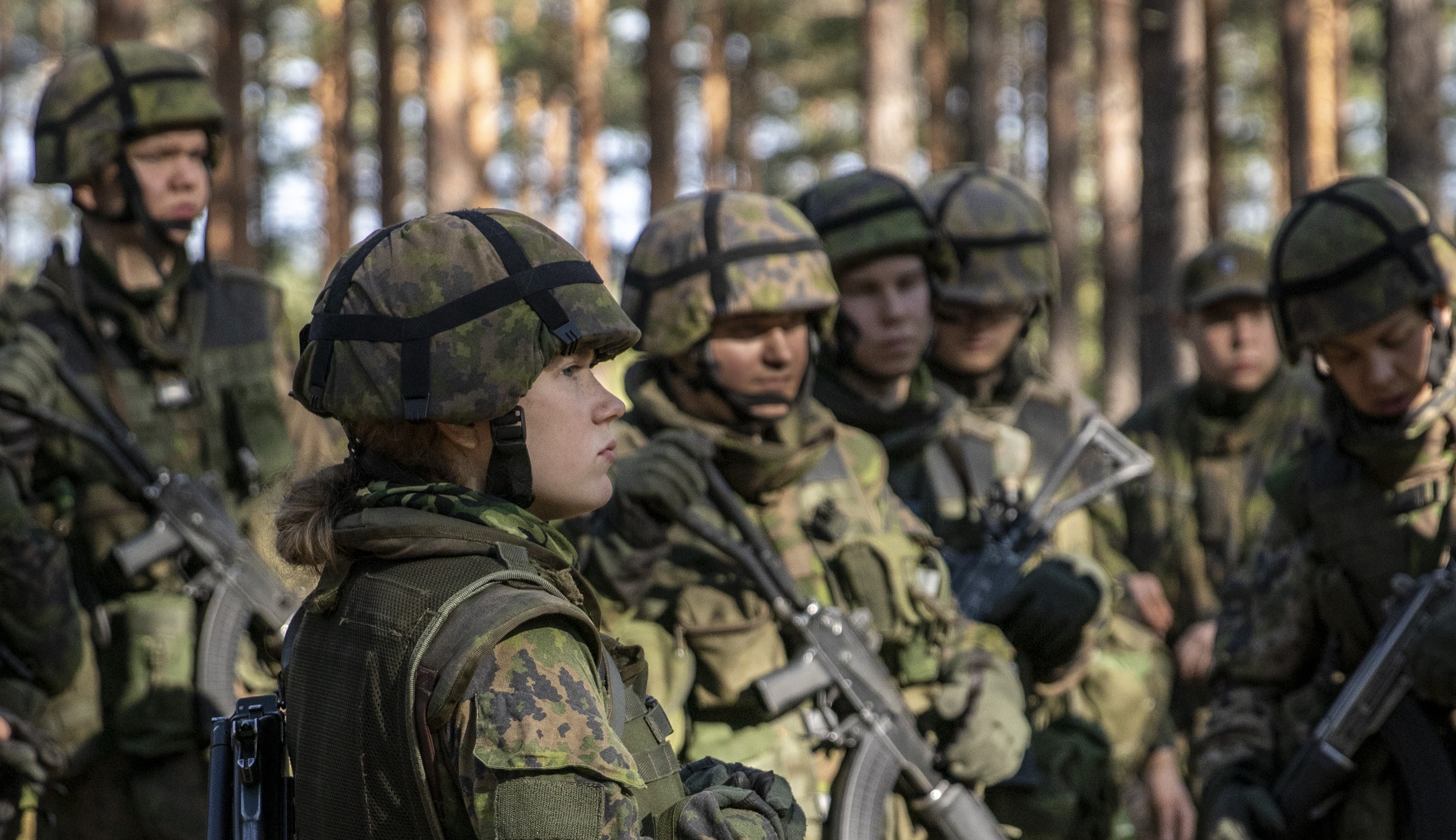 En kvinna som fullgör frivillig militärtjänst och beväringar i skogen under övningen.