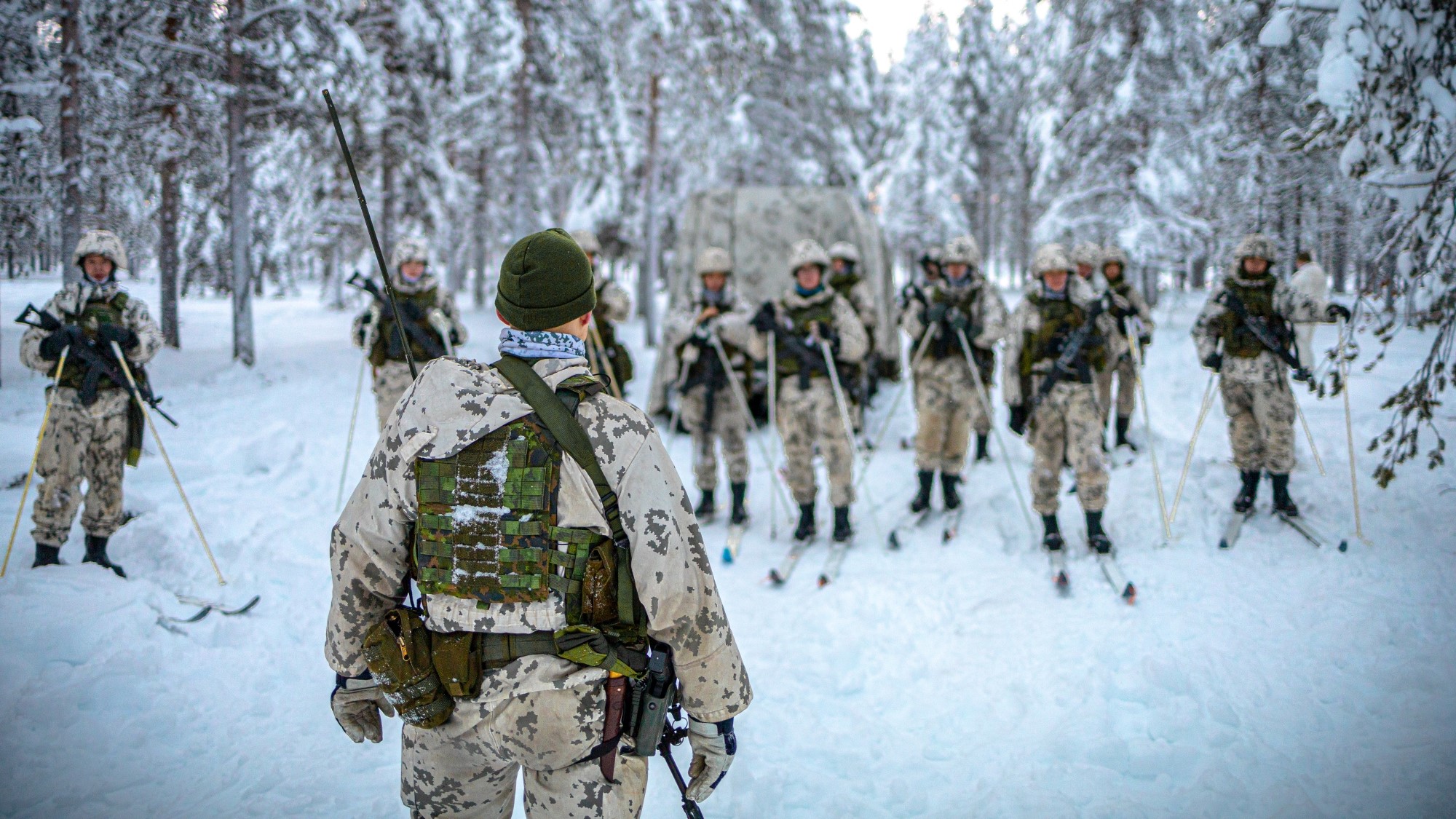 Varusmiehiä hiihtää talvisessa metsässä.